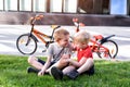 Two boys communicate sitting on the grass. Rest after cycling, bicycles in the background Royalty Free Stock Photo