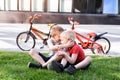 Two boys communicate sitting on the grass. Rest after cycling, bicycles in the background Royalty Free Stock Photo