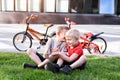 Two boys communicate sitting on the grass. Rest after cycling, bicycles in the background Royalty Free Stock Photo