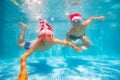 Two boys dive in pool on vacation wear Sant hats