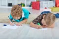 Two boys draw Santa Claus on the paper on the floor in the nursery.