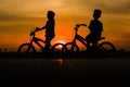 two boys enjoying the sunset on a bicycle