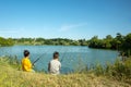 Two boys with fishing rods catch fish on the pond with a grandfather