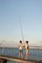 Two boys is fishing at sunset on the lake. Kids are playing on nature with fishing rod. Royalty Free Stock Photo