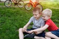 Two boys are gaming on the smartphone while sitting on the grass. Bicycles in the background Royalty Free Stock Photo