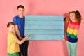 Two boys and a girl are holding a blank poster for inscription and text Royalty Free Stock Photo