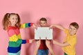 Two boys and a girl are holding a blank poster for inscription and text Royalty Free Stock Photo