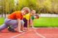 Two boys and girl stand on knee ready to run Royalty Free Stock Photo