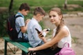 Two boys and girl use their phones during school breack. Cute boys sitting on the bench and play online games Royalty Free Stock Photo