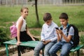 Two boys and girl use their phones during school breack. Cute boys sitting on the bench and play online games Royalty Free Stock Photo