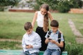 Two boys and girl use their phones during school breack. Cute boys sitting on the bench and play online games Royalty Free Stock Photo