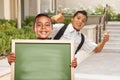 Two Boys Give Thumbs Up Holding Blank Chalk Board on Campus