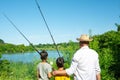 Two boys and grandfathers went fishing. They stand on the shore of the pond and look into the distance