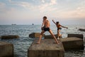 Two boys jumping on concrete blocks on the seashore