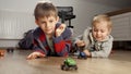 Two boys lying on wooden floor and having toy car race. Children playing, development and education, games at home Royalty Free Stock Photo