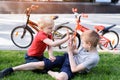 Two boys are photographed on a smartphone while sitting on the grass. Rest after cycling, bicycles in the background Royalty Free Stock Photo