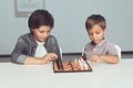 Two boys play chess sitting at a table and are bored. Royalty Free Stock Photo