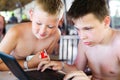 Two boys play a laptop on rest in a bar on a beach