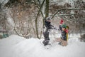 Two boys play on a pile of snow after heavy snowfall in the city. Children on a walk in the park in winter. Active healthy Royalty Free Stock Photo