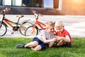 Two boys play sitting on the grass. Rest after cycling, Bicycles in the background Royalty Free Stock Photo