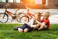 Two boys play sitting on the grass. Rest after cycling, Bicycles in the background Royalty Free Stock Photo