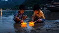 Two boys playing with glowing lotus candles in the water at dusk Royalty Free Stock Photo