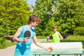 Two boys playing together ping pong outside