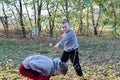 Two boys are playing with yellow autumn leaves under a tree in the garden . Royalty Free Stock Photo