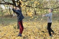 Two boys are playing with yellow autumn leaves under a tree in the garden Royalty Free Stock Photo