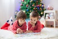 Two boys, reading a book in front of Christmas tree Royalty Free Stock Photo