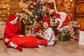 Two boys in red clothes open gifts sitting under the Christmas tree Royalty Free Stock Photo