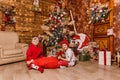 Two boys in red clothes open gifts sitting under the Christmas tree Royalty Free Stock Photo