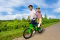 Two boys riding same bike and both stand