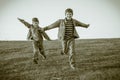 Two boys running together on meadow, sepia toned Royalty Free Stock Photo