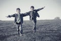 Two boys running together on meadow, sepia toned Royalty Free Stock Photo