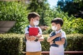 Two boys, schoolchildren in black school uniforms with backpacks in a medical mask go to school independently, hold hands, Royalty Free Stock Photo