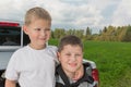 Two boys siiting on a car trunk