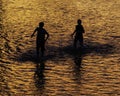 Two boys silhouetted against orange water