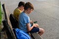 Two boys sitting on a bench with their backpacks and cell phones.Top view Royalty Free Stock Photo