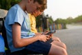 Two boys sitting on a bench with their cell phones Royalty Free Stock Photo