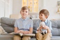 Two boys sitting on couch are reading book. Older brother reads interesting Royalty Free Stock Photo