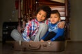 Two boys sitting inside suitcase.