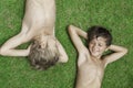 Two boys smile lying on a green grass