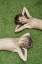 Two boys smile lying on a green grass