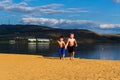 Two boys in sports shorts running on the yellow sand on the beach, holding hands Royalty Free Stock Photo