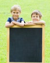 Two boys standing at the blackboard outdoor. Green background.