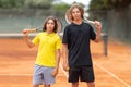Two boys standing on the tennis court holding raquets Royalty Free Stock Photo