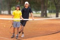 Two boys standing on the tennis court leaning on the net holding racquets and looking in the camera Royalty Free Stock Photo