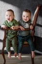 Two boys twins at the age of one year sitting next on the armchair