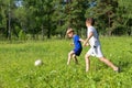 Two boys in uniform plays football on a meadow. Children run and kick a soccer ball. Summer outdoor games Royalty Free Stock Photo